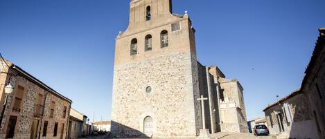 A historic stone church with a bell tower, cobblestone street, and traditional buildings.