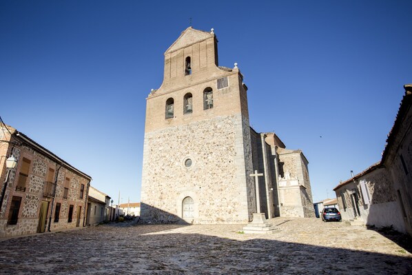 A historic stone church with a bell tower, cobblestone street, and traditional buildings.