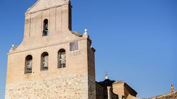 A historic church with a bell tower, stone walls, and a tiled roof.