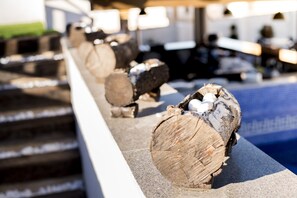 Logs lined up on a ledge with a pool in the background.