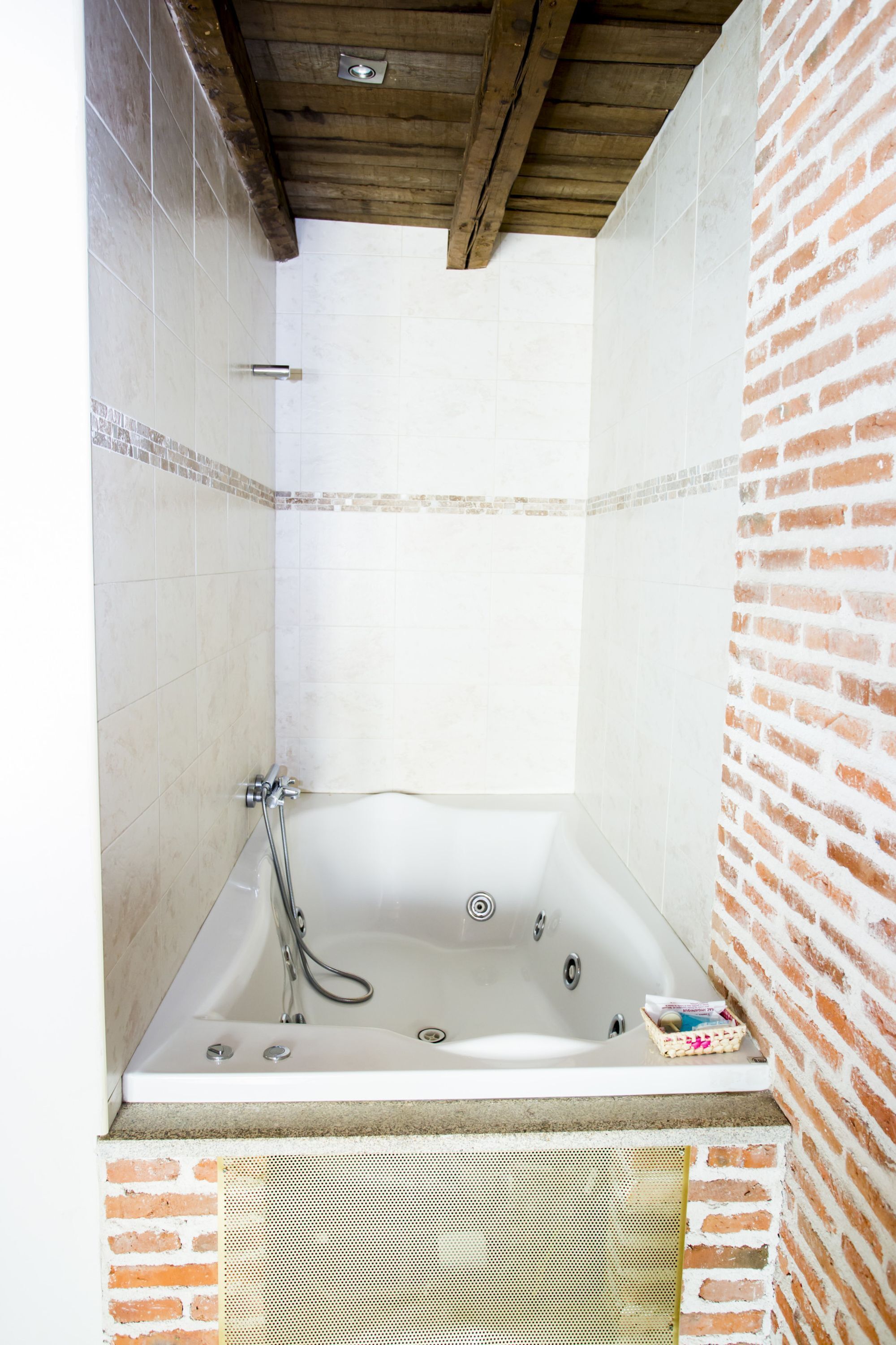 A bathroom with a freestanding bathtub, tiled walls, and a brick accent wall.