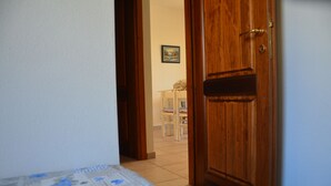 A doorway leading to a room with a bed, a wooden door, and a painting on the wall. - Fta-bel01 APT 6 PAX Vicino AL Mare (Budoni)