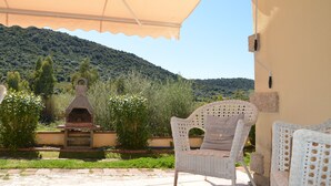 A patio with a brick oven, white wicker chairs, and a view of a hillside. - Fta-bel01 APT 6 PAX Vicino AL Mare (Budoni)