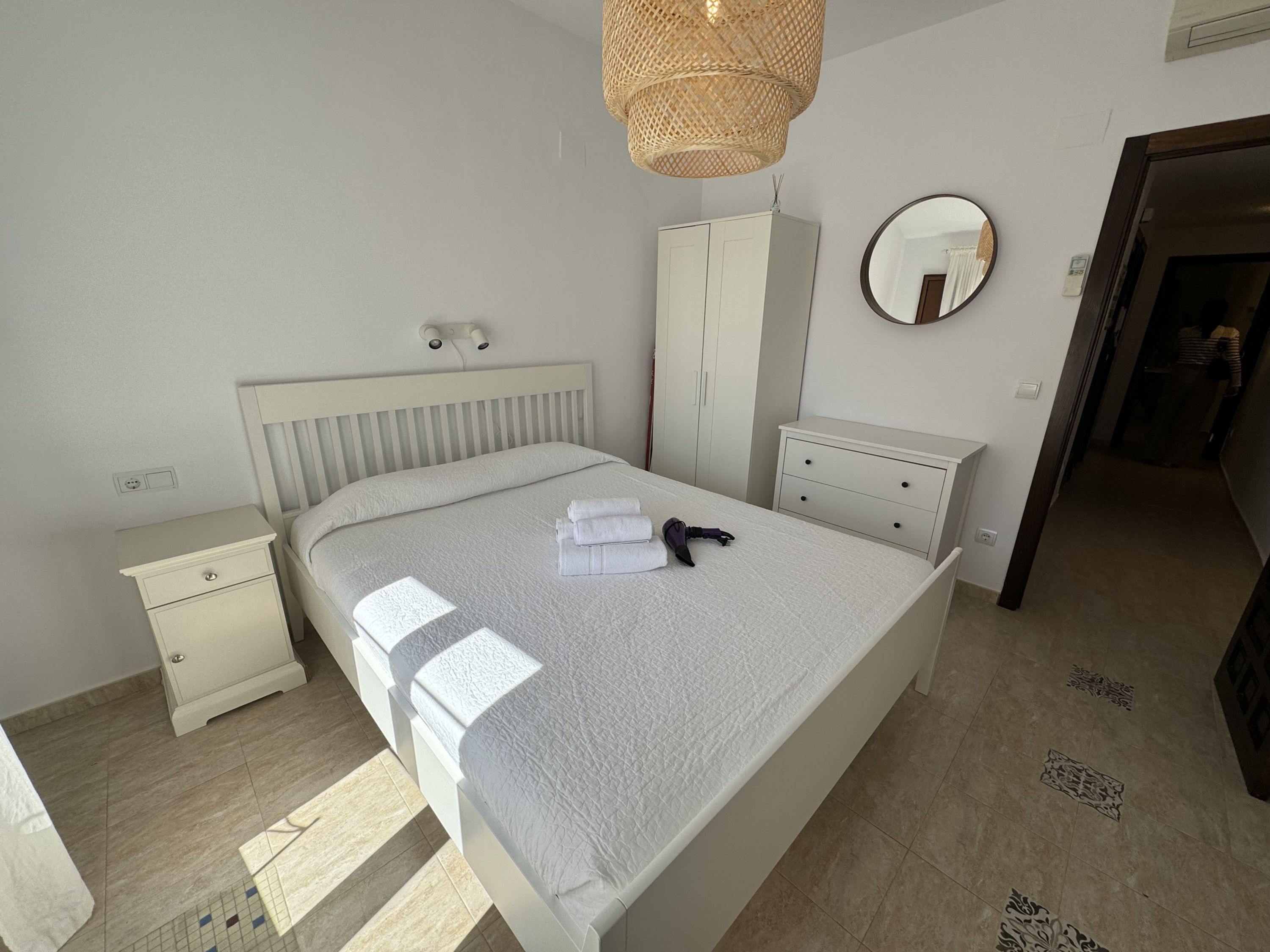 Un dormitorio con cama, mesita de noche, armario y espejo.