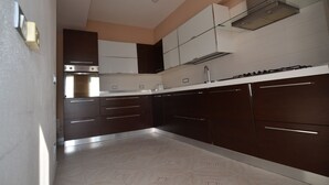 A modern kitchen with dark cabinetry, a stainless steel range hood, and a tiled backsplash. - Fta-bel02 APT 6 PAX Vicino AL Mare (Budoni)