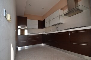 Una cocina moderna con armarios oscuros, una campana extractora de acero inoxidable y un salpicadero de azulejos.