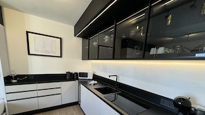 A modern kitchen with black countertops, white cabinets, and a black backsplash.