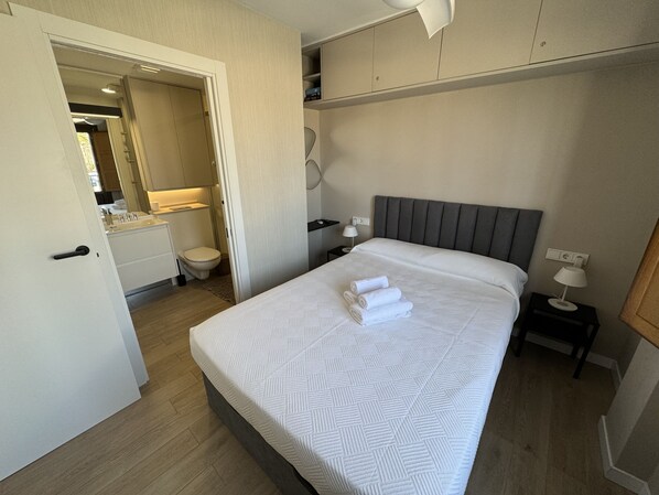 A hotel room with a bed, bedside table, and a bathroom visible through an open door.