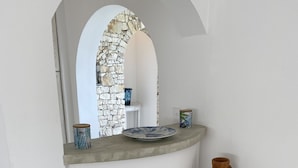 A kitchen area with a curved countertop, a stone wall, a woven basket, and a ceramic pot. - Villa d Exception vue mer Panoramique Piscine (Saint-Florent)