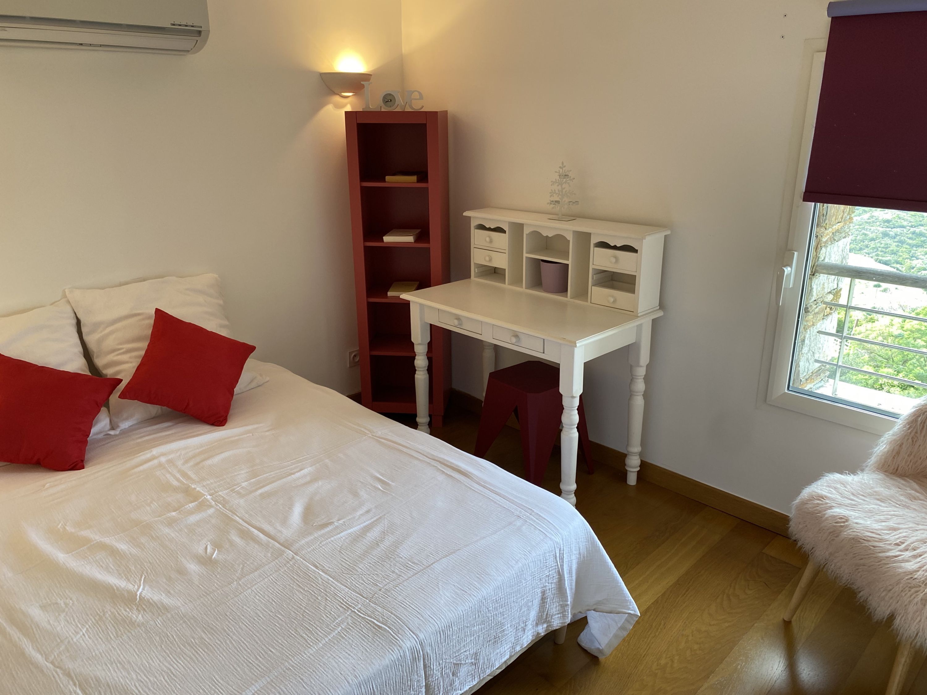 Una camera da letto con un letto, una scrivania, una libreria e una finestra con vista.