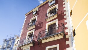 Un immeuble à plusieurs étages, doté de balcons, d’une porte bleue et de plantes en pot.