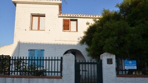 A white building with a tiled roof, a green gate, and a sign indicating available rooms. - Fpo-rose02p1 in Ottiolu (Budoni)