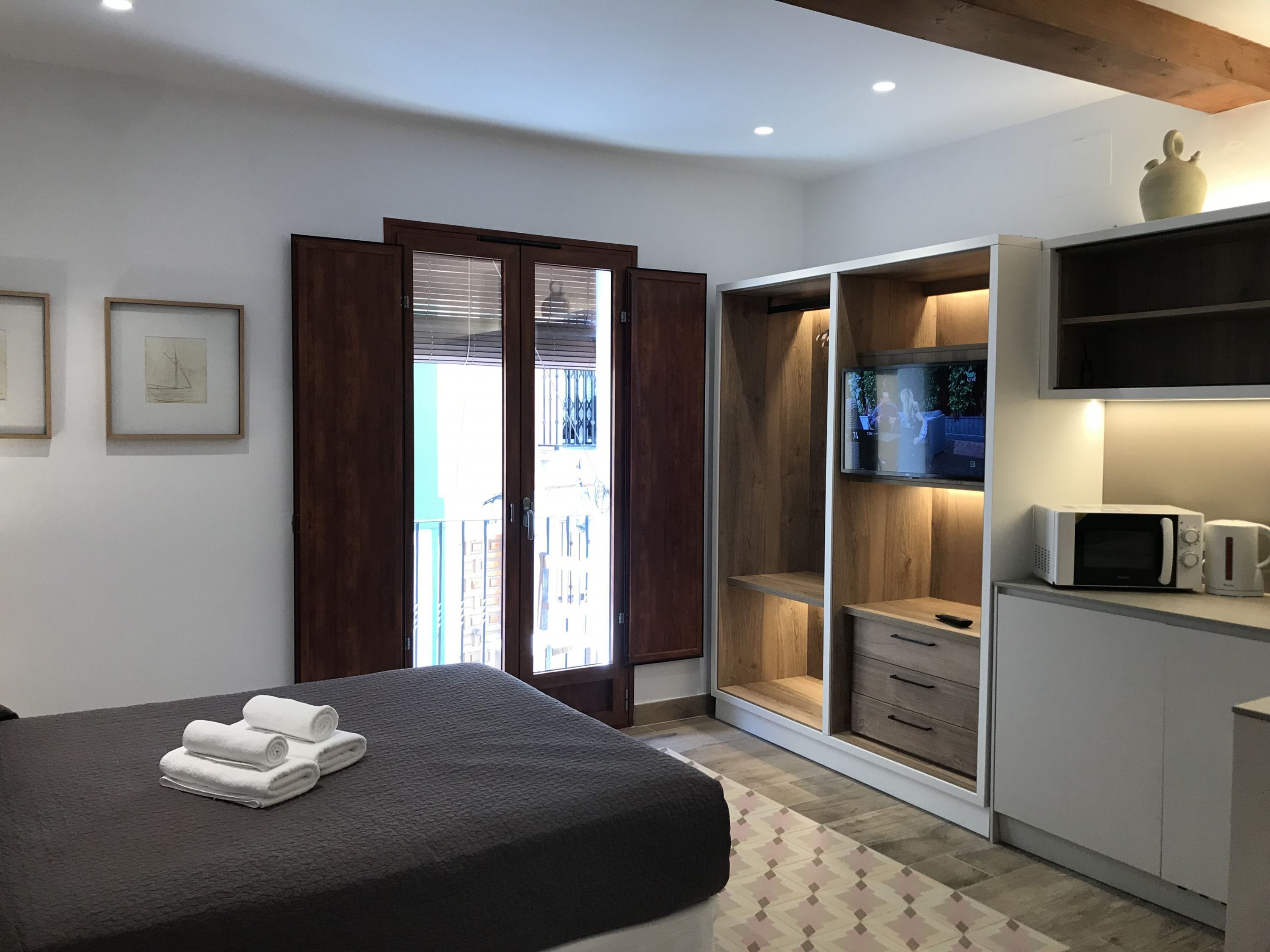 A bedroom with a bed, a TV, a microwave, and a wardrobe.