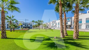 A golf course with palm trees and modern buildings in the background. - Casa Nicola in Guardamar (Guardamar del Segura)