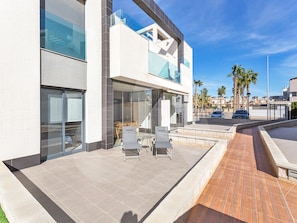 A modern building with a patio area featuring outdoor seating and a pathway. - Casa Nicola in Guardamar (Guardamar del Segura)