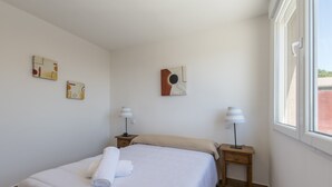 A neatly made bed with a white duvet, two bedside tables with lamps, and abstract wall art. - VI El Cuartel 2 in Vila (Villatoro)