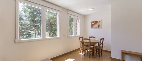 A room with large windows, a dining table, and chairs.