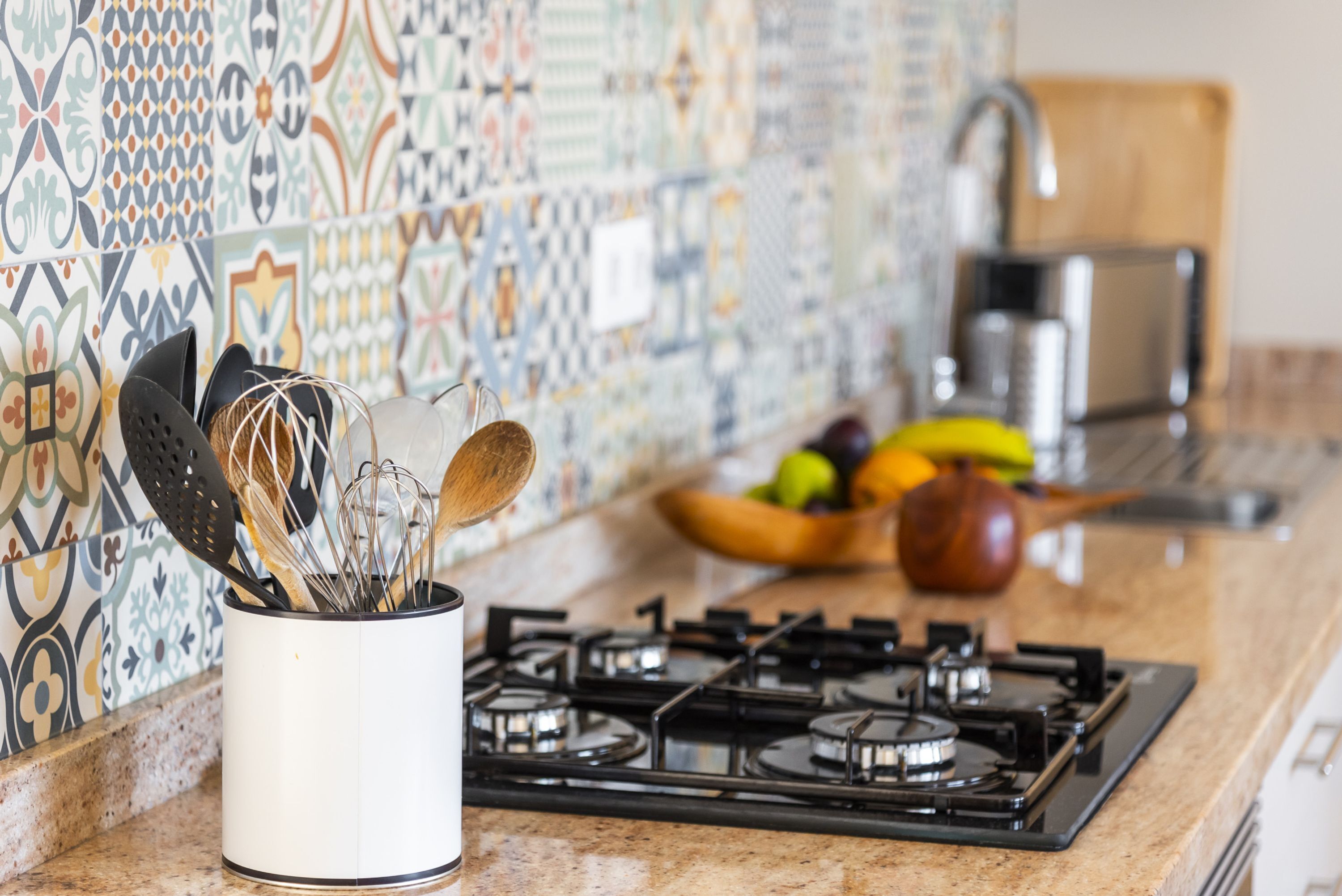 Una cocina con estufa a gas, un utensilero blanco y un salpicadero con estampado.