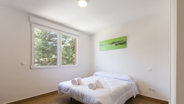 Een slaapkamer met een bed, een raam en een groene schildering aan de muur.
