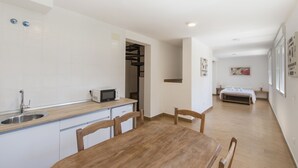 Een moderne keuken met een houten eettafel en stoelen, een inbouwmagnetron en een spoelbak.