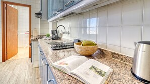 A modern kitchen with granite countertops, a gas stove, and a bowl of bananas. - Retreat w Ocean Views Private Parking Ensuite (Los Realejos)