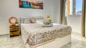 A bedroom with a bed, a bedside table, a lamp, a painting, and a window with curtains. - Two-floor Penthouse w Complex Pool Outdoor Terrace (Arona)