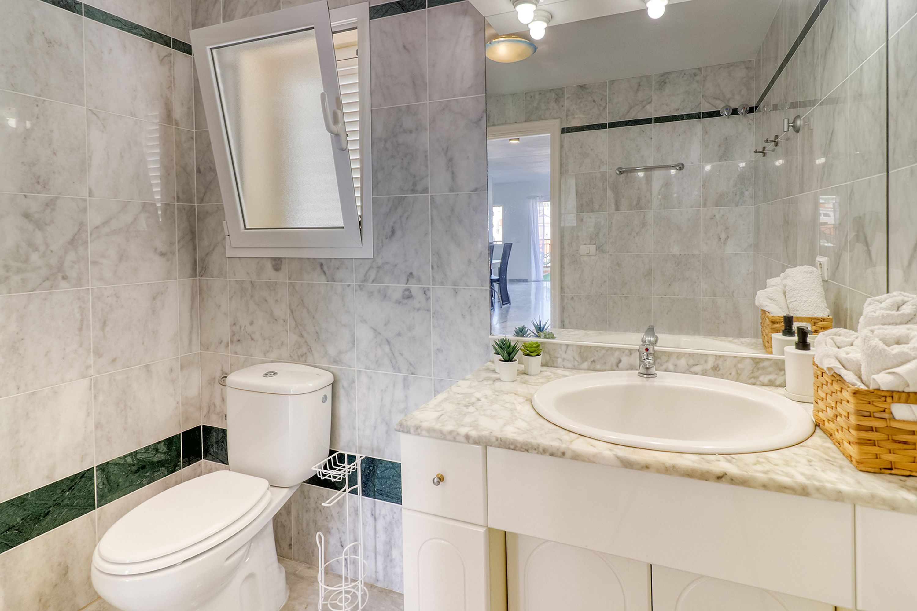 Ein modernes Badezimmer mit Toilette, Waschbecken und Spiegel.