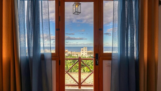 Eine Holztür mit Blick auf das Meer und Gebäude durch ein Glasfenster.