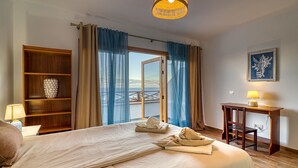 Ein Hotelzimmer mit einem Bett, einer Holzwandregal mit Dekoration, einem Schreibtisch mit Lampe und Blick auf eine Brücke durch das Fenster.