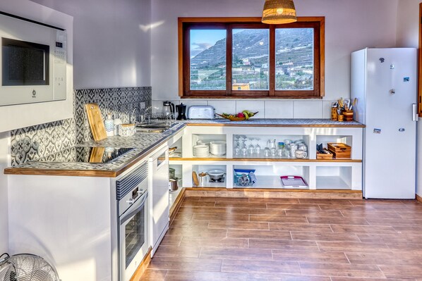 Een moderne keuken met een inbouwoven, magnetron en een groot raam met uitzicht op de bergen.