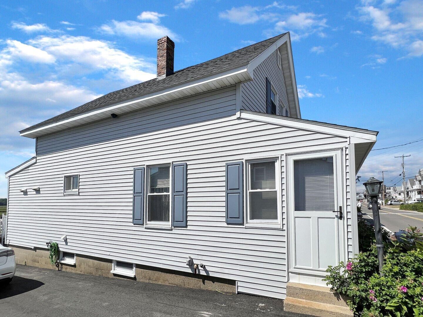 Une maison de plain-pied avec un toit à pignon, une cheminée et une porte de garage.