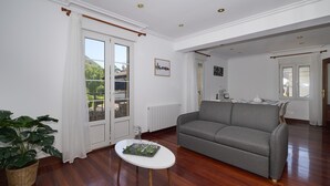 A living room with a grey sofa, a small white table, and a potted plant. - Great Escape by Fidalsa (Gautegiz Arteaga)