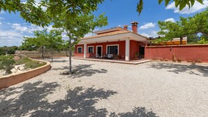 Una casa roja con techo de tejas, rodeada de grava y árboles.