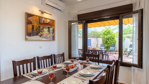 Un comedor con una mesa dispuesta para seis, un cuadro en la pared y una puerta corredera abierta al exterior.