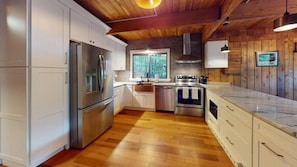 A modern kitchen with white cabinetry, stainless steel appliances, and a wooden floor. - Treehouse Home in Ludlow (Ludlow)