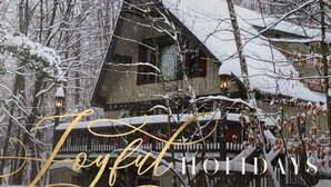 A cozy cabin with a steep roof, surrounded by snow-covered trees, and a warm interior light visible through the window. - Treehouse Home in Ludlow (Ludlow)