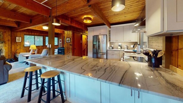 A spacious kitchen with a large island, wooden ceiling beams, and modern appliances. - Treehouse Home in Ludlow (Ludlow)
