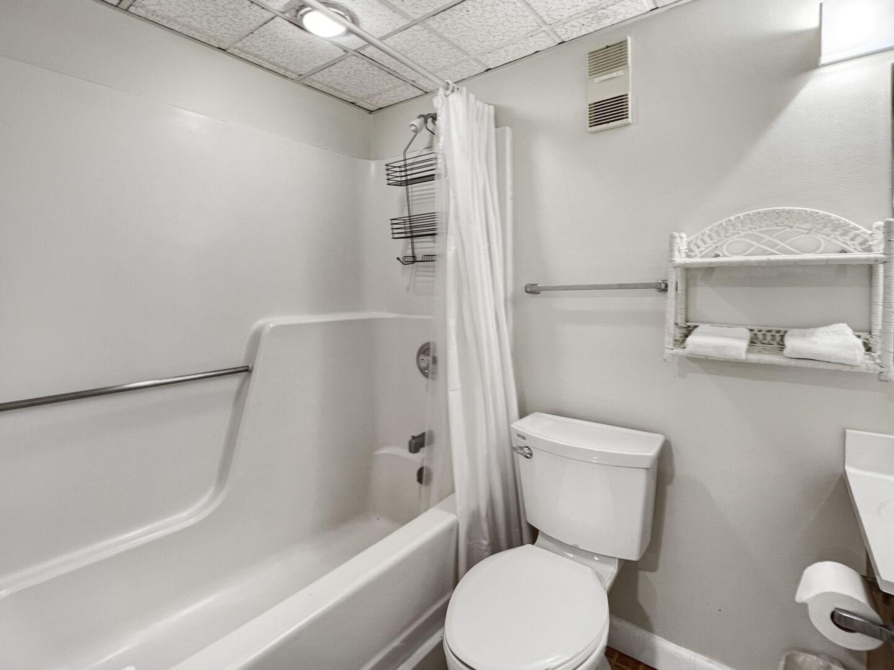 A bathroom with a bathtub, toilet, and shower curtain.