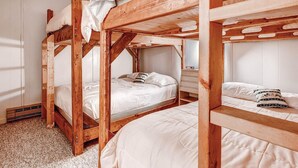Ein Zimmer mit Etagenbetten, Holzbalken und weißer Bettwäsche.