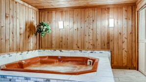 Ein Zimmer mit Holzwänden, einer Badewanne und einem gefliesten Boden.