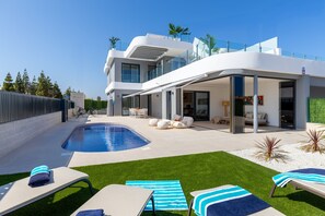 Uma casa moderna com piscina, área de estar externa e um terraço coberto.