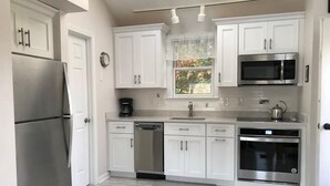 A modern kitchen with white cabinets, stainless steel appliances, and a skylight. - Perkins Cove Gem - Q934 (Ogunquit)