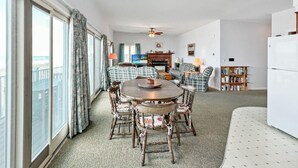A spacious living room with a large window, a dining area with a round table and chairs, a fireplace, and a ceiling fan. - Sandcastle - W148 in Wells (Wells)