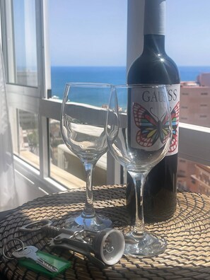 A bottle of Gauss wine and two glasses on a table by a window with a view of the sea.