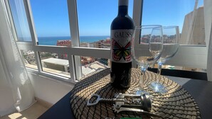 A bottle of Gauss wine, a wine glass, a bottle opener, and a key on a woven mat by a window with a city view. - Tina de Steram Flats Torremolinos (Torremolinos)