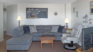A living room with a sectional sofa, a round coffee table, a TV, and two lamps. - Sea Breeze - W007 in Wells (Wells)