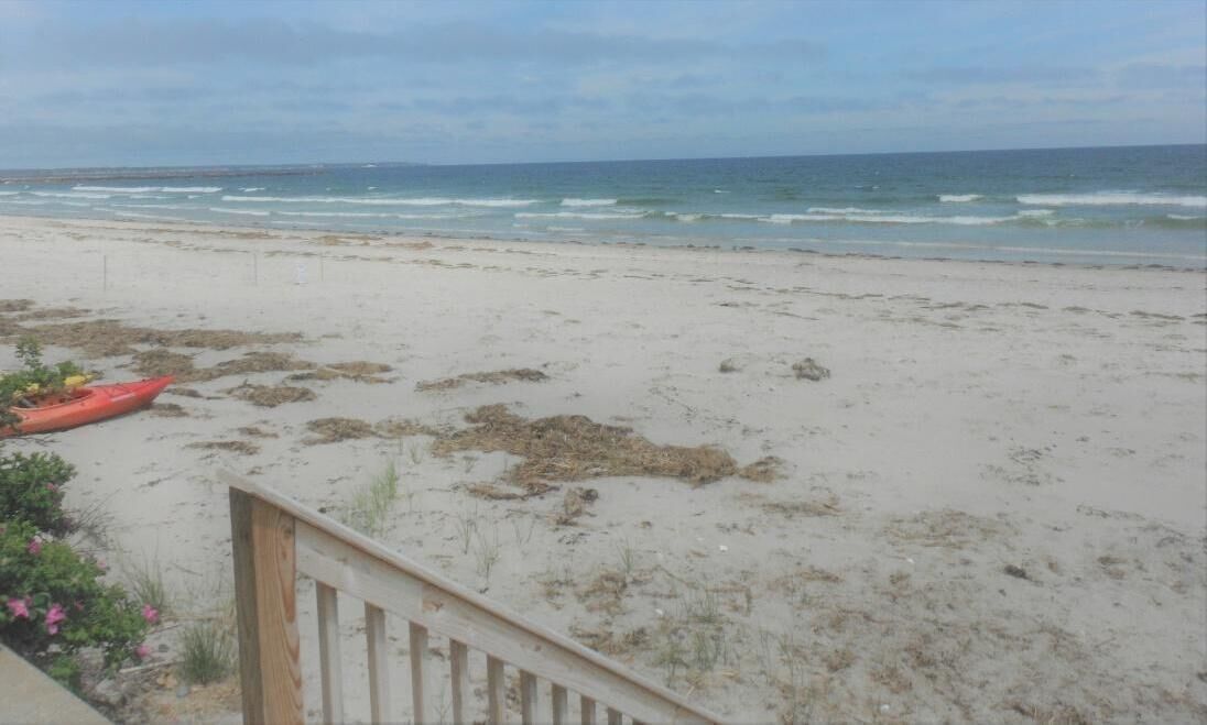 A beach with a wooden fence and a red kayak.