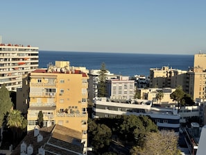 Ένα παραθαλάσσιο αστικό τοπίο με ψηλά κτίρια, μερικά από τα οποία διαθέτουν μπαλκόνια και κεραίες δορυφορικής τηλεόρασης, και με καθαρή θέα στη θάλασσα.