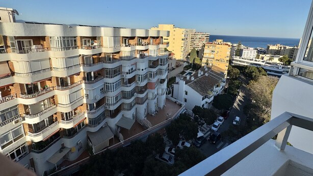 A multi-story residential building with balconies, a courtyard, and a view of the sea.