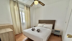 A neatly made bed with a headboard, a bedside table, and a nightstand.